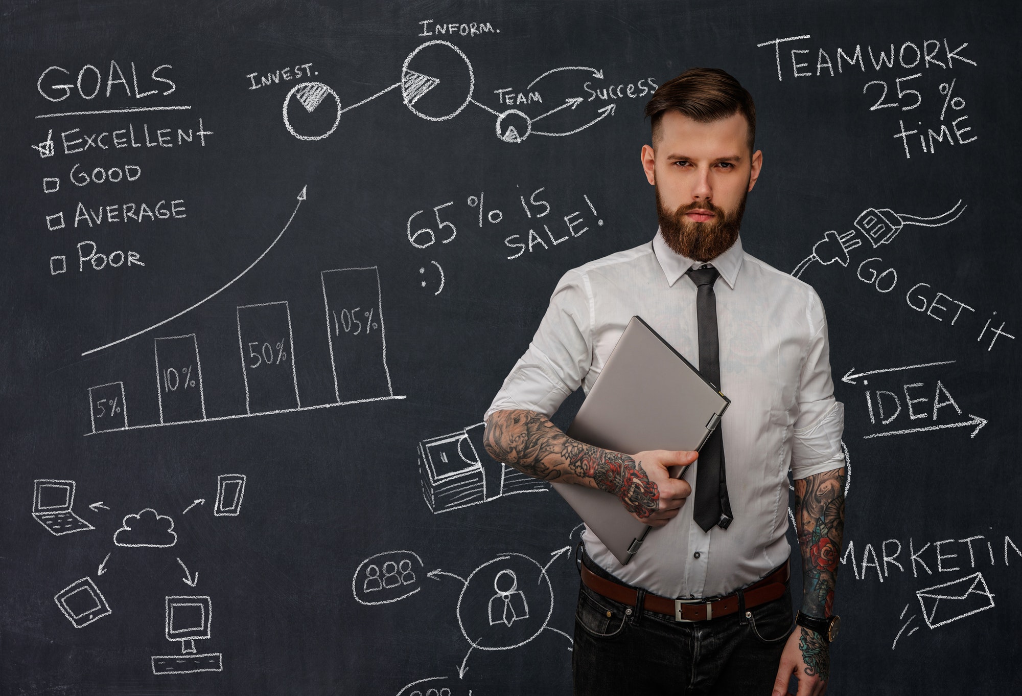 Tattooed bearded techer with laptop.